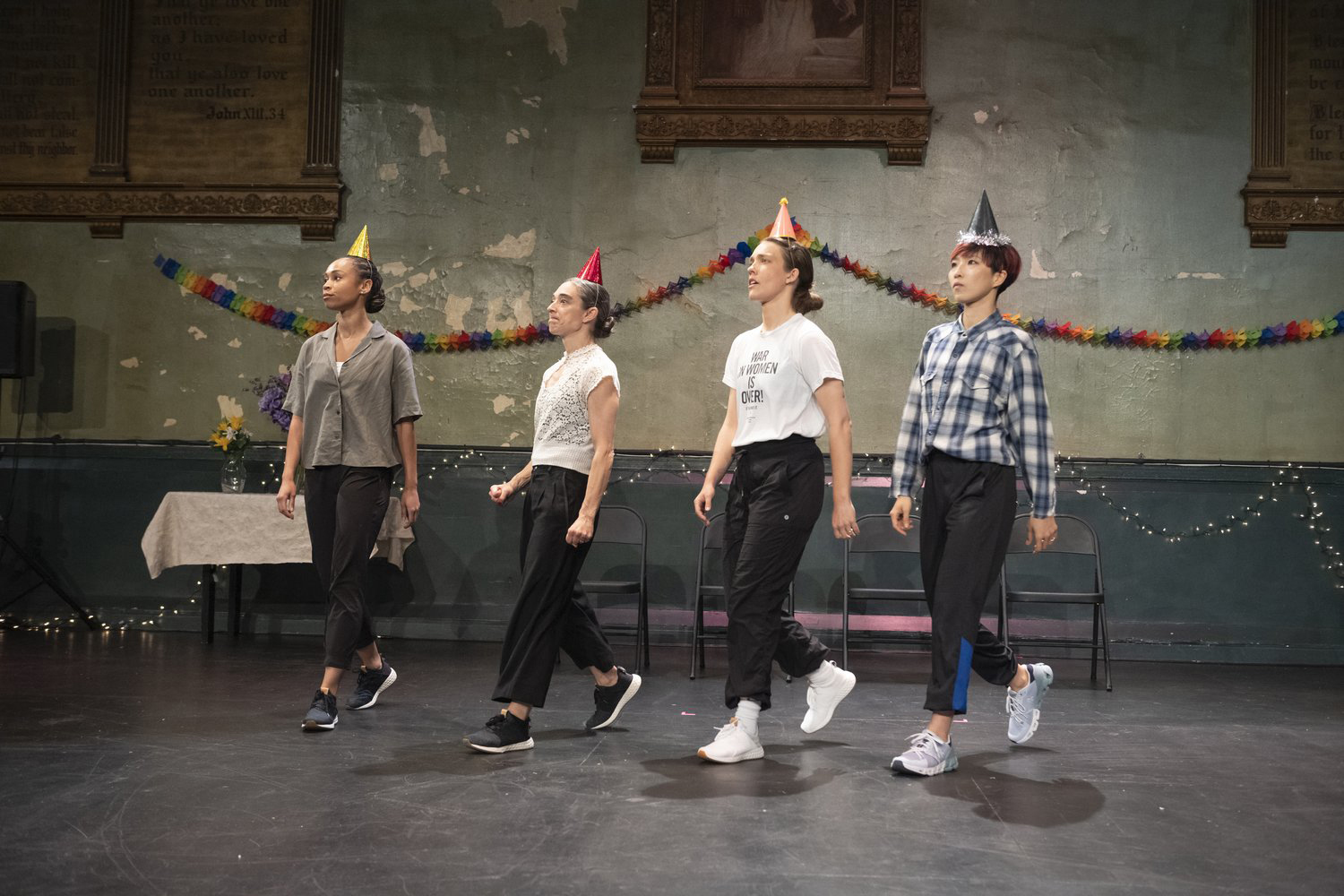 four dancers standing side by side on stage wearing party hats