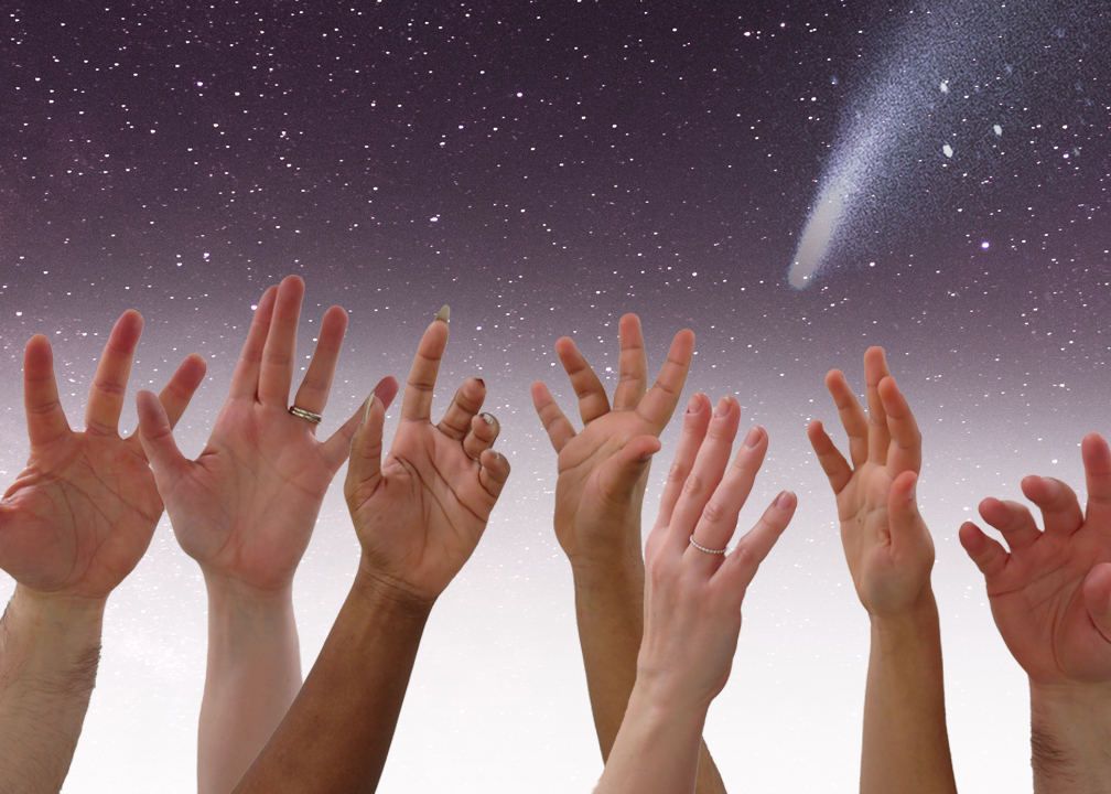 various people's hands reaching towards the night sky where a shooting star is visible