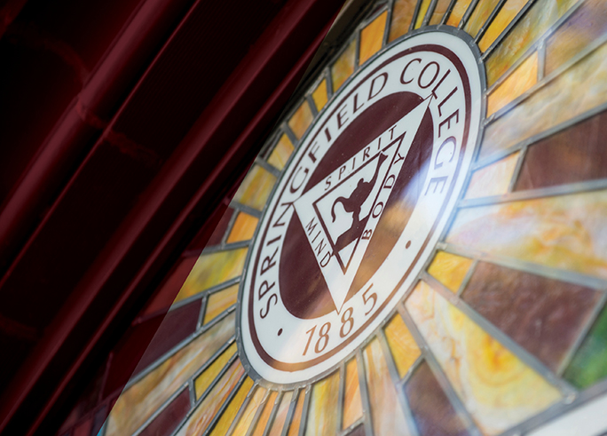 a stained glass window featuring the Springfield College seal