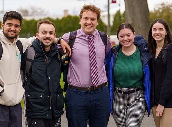 A group of five graduate students standing together on the Springfield College campus