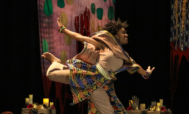 photo of a female dancer jumping across the stage during a performance