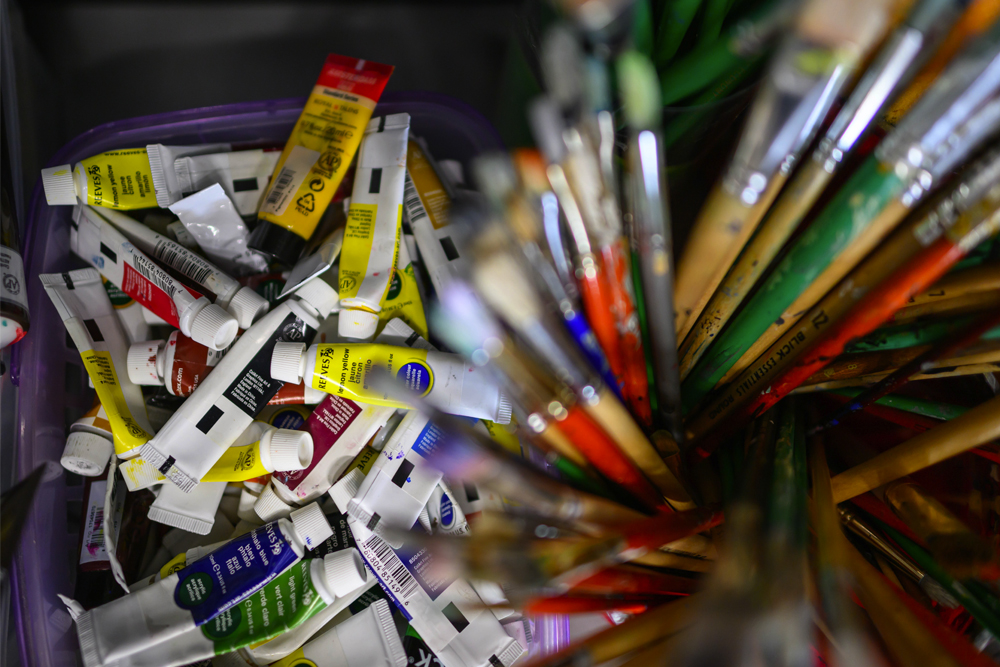 A close up photo of paint brushes and tubes of paint used by artists