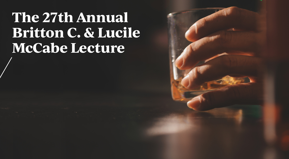 photo of a hand holding a glass of whiskey at a bar