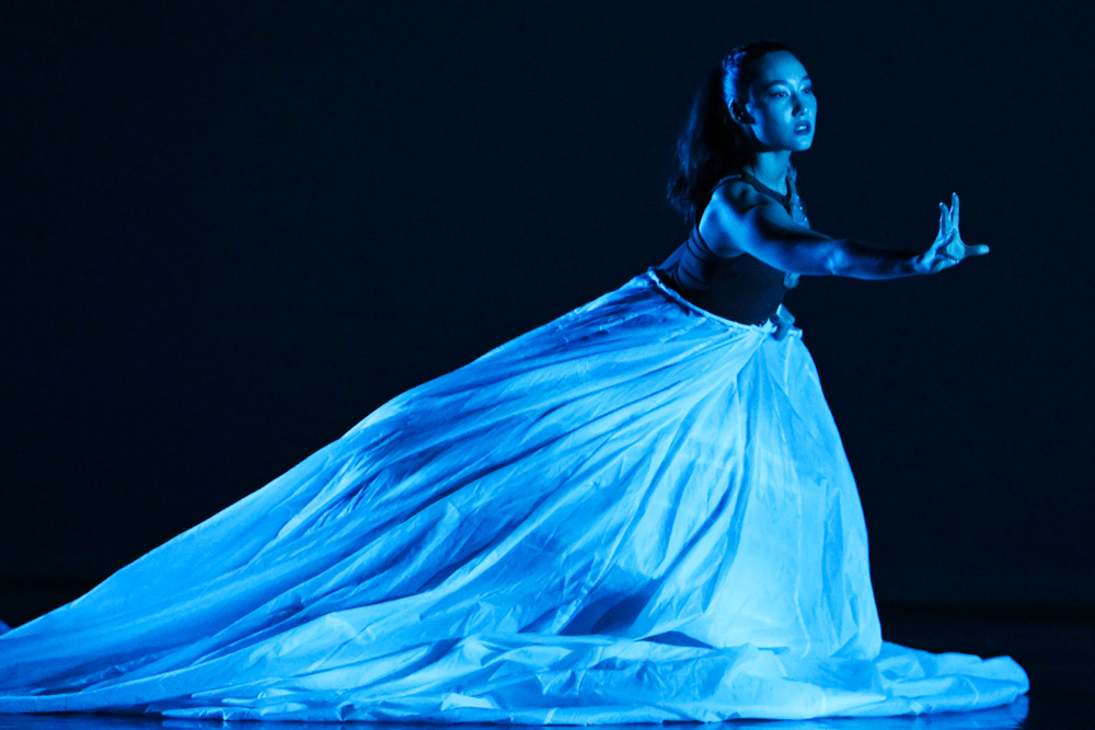 Photo of a dancer performing on stage in a blue spotlight