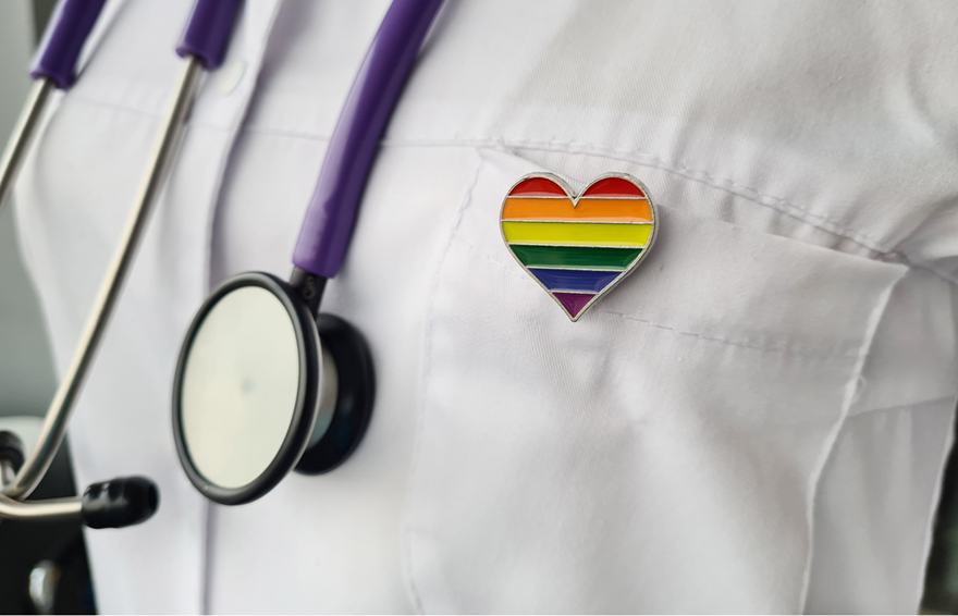 close up of a doctor's white coat showing a stethoscope and a rainbow heart pin